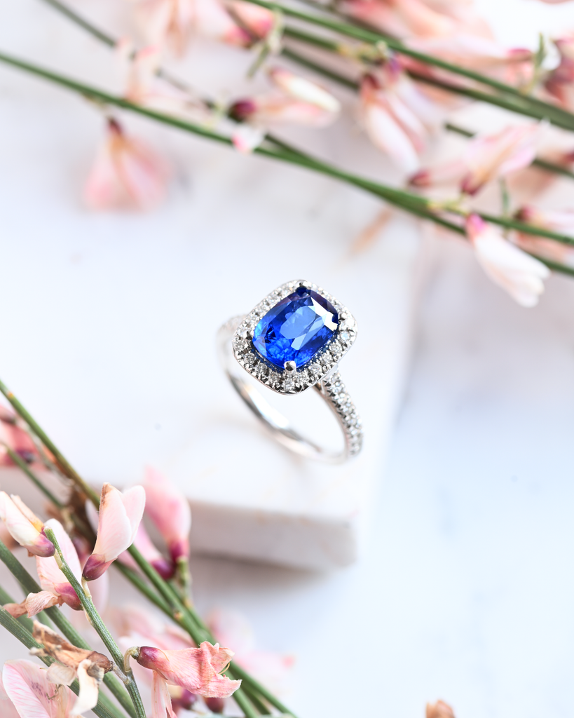 large blue sapphire and diamond halo ring surrounded by pink flowers